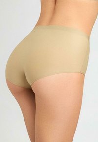 Beżowe, bezszwowe majtki w stylu boyshorts o gładkiej fakturze i elastycznym pasku w talii, zaprojektowane z myślą o komforcie i dyskretnym noszeniu pod odzieżą.