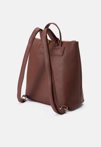 Mochila de pele castanha com alças ajustáveis, formato retangular, detalhes em metal dourado e abertura com fecho. Textura suave, design minimalista.