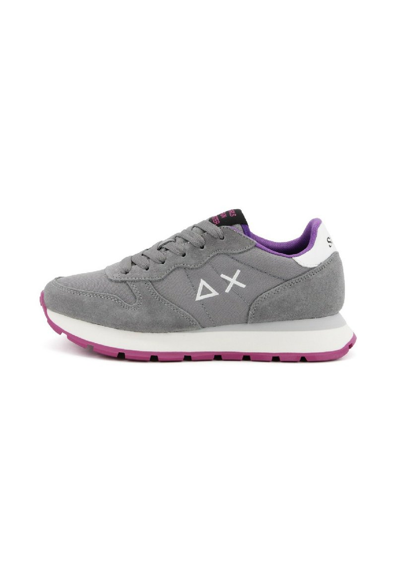 Sneaker in suede grigia con una suola intermedia bianca piatta e suola esterna viola. Presenta una linguetta in rete, lacci grigi e accenti bianchi del logo sui lati.