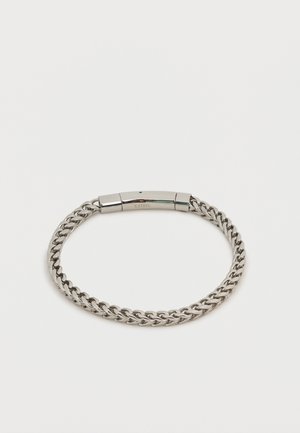 Męska bransoletka łańcuchowa ze stali nierdzewnej z polerowanym, gładkim, prostokątnym zapięciem grawerowanym napisem "S. STEEL" na białym tle.