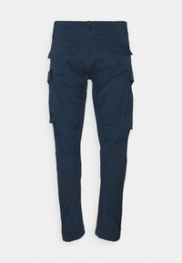 Granatowe spodnie cargo o slim fit, z bocznymi kieszeniami, gładką teksturą oraz klasycznym designem pasa. Widoczne detale tylnej kieszeni.