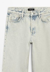 Jean bleu clair effet acidulé avec passants de ceinture, poches avant, fermeture à bouton et étiquette de la marque Massimo Dutti à l'intérieur de la ceinture.
