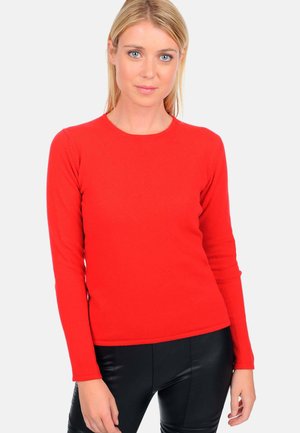 Haut rouge à manches longues en tissu tricoté extensible, avec un col rond et une silhouette ajustée, associé à un pantalon noir.