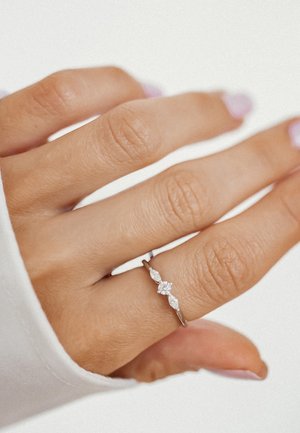 Silver ring with a delicate twisted design, featuring a central round stone and two marquise stones on either side.