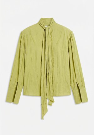 Ανοιχτό πράσινο μπλουζάκι με μακριά μανίκια, ψηλό γιακά, ραφές στο μπροστινό μέρος και μια μακριά, λεπτή γραβάτα που κρέμεται στο κέντρο.