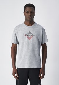 Camiseta gris de manga corta hecha de tela suave, con un gráfico de diamante en negro, rojo y blanco en el centro.