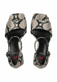 Sandali open-toe in stampa serpente nera e beige con design a strap incrociati, con una soletta in pelle nera e un accento rosso sulla suola.