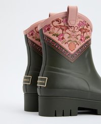 Groene rubberen regenlaarzen met een roze decoratieve bovenkant, versierd met bloemen- en dierenmotieven. Bevat een treklip en een structuurzool voor grip.