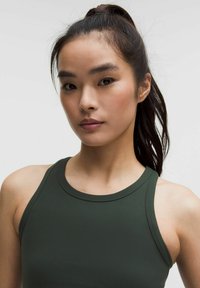 Tumši zaļš sporta topiņš ar augstu apkakli un platām siksnām, kas izgatavots no gludas, elastīgas auduma un ir pieguļošas formas.