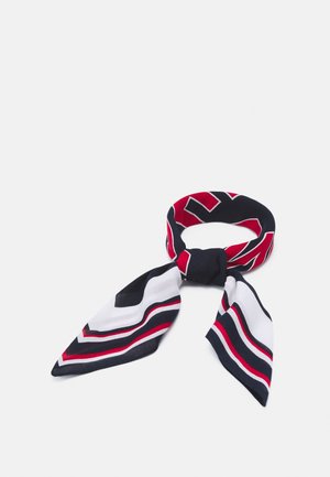 Silketørklæde med røde, hvide og marineblå geometriske striber bundet i en løs knude på en hvid baggrund.