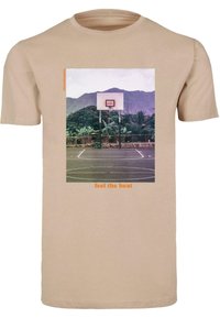 Bežové bavlnené tričko s grafikou basketbalového koša na pozadí hôr a textom "cítite horúčavu" v oranžovej farbe.