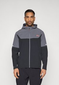 Μαύρο και γκρι μπουφάν με κουκούλα και φερμουάρ, με σχεδιασμό σε μπλοκ χρωμάτων, ανακλαστικές λεπτομέρειες στα μανίκια και λογότυπο Under Armour.