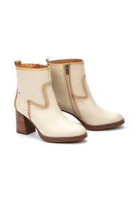 Cream leather ankle boots with a side zipper, stacked heel, and decorative stitching detail. Smooth texture and minimalist design.