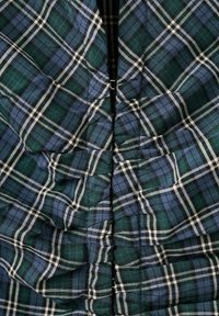 Țesătură în carouri verde închis și albastru închis cu dungi albe, adunată și cusută împreună în centru, formând un efect plisat.