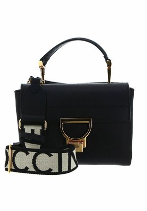 Sac à main en cuir noir avec ferrures dorées, une poignée supérieure, et une large bandoulière en tissu noir et blanc à logo de marque.