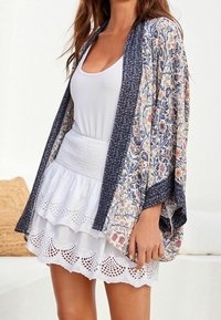 Luźny kimono w kwiatowe wzory w kolorze granatowym i kremowym, połączone z białą spódnicą z marszczeniem, z wypustkami i warstwowymi falbanami.