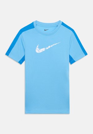 Ανοιχτό μπλε αθλητικό μπλουζάκι Nike με κοντά μανίκια, πιο σκούρες μπλε ρίγες στους ώμους και λευκό παραμορφωμένο λογότυπο Nike swoosh στο στήθος.