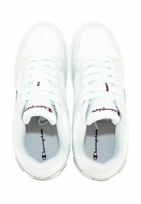 Baskets blanches de sport avec une tige synthétique lisse, des perforations sur la boîte à orteils, des lacets plats et un logo "Champion" rouge sur la languette.