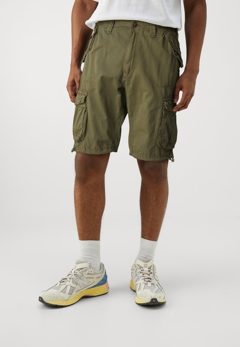 Gröna cargoshorts med flera sidofickor, en lös passform och sömnadsdetaljer. Bärs med ljusa sportskor och strumpor.