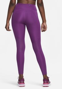 Leggings deportivos morados con cintura alta, textura suave y acentos de panel de malla, que presentan un diseño ajustado y costuras distintivas.