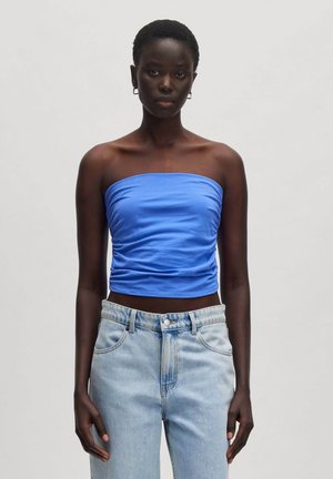 Trägers Top in Blau aus dehnbarem Material, mit geraffter Textur am Oberkörper, kombiniert mit hellblauen High-Waist-Jeans.