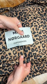 Leopardi print kangas pruunide ja mustade toonidega, tekstuurse pinnaga. Sildil on kirjutatud "MAIS NØRGAARD COPENHAGEN."