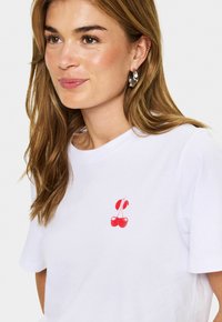 Weißes Baumwoll-T-Shirt mit einer kleinen roten Kirsche auf der linken Brust, kurzen Ärmeln und Rundhalsausschnitt.