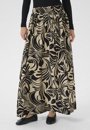 Beige maxi skirt with black bold tropical leaf print, elastic waistband, worn with black top and black ballet flats.