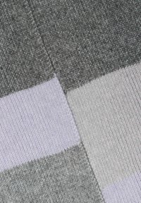 Close-up of knitted fabric with gray, light gray, and pale purple striped pattern and visible seam stitching.