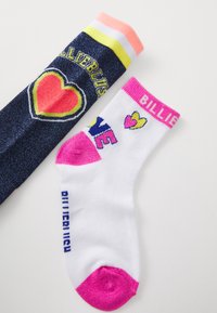 Två par strumpor: ett par marinblå med ett hjärtdesign i gult och rosa, och ett vitt par med regnbågstext och rosa detaljer.