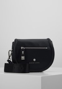 Černá kožená crossbody taška zaobleného tvaru, se stříbrnými kovovými doplňky, zipovým uzávěrem, s logem na přední straně a nastavitelným textilním popruhem.