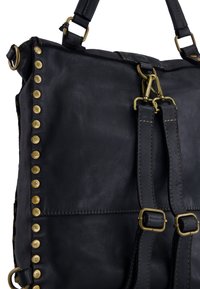 Sort lædertaske med messingnitter langs siden, justerbare stropper og en trykknaplukning, der viser en glat tekstur og solidt beslag.