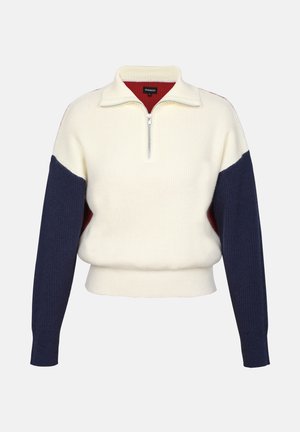 Sudadera con cremallera en color crema y textura acanalada. Presenta mangas en azul marino y un cuello interior rojo para contraste. Diseño corto.