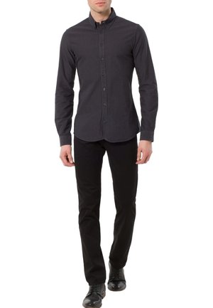 Camisa gris oscuro abotonada con cuello, mangas largas y corte entallado, combinada con pantalones negros y zapatos negros para un look armonioso.