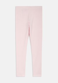 Jasnoróżowe legginsy wykonane z miękkiego, elastycznego materiału. Dopasowany krój o gładkiej fakturze, bez widocznych wzorów czy elementów metalowych.