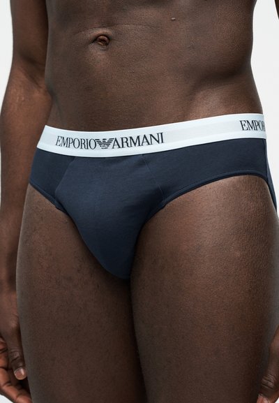 Άνδρας σώμα με ναυτικό μπλε εσώρουχα που έχουν λευκή μέση με το λογότυπο Emporio Armani.