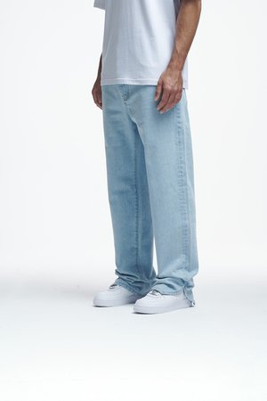 Jean en denim bleu clair avec une coupe décontractée, porté avec un t-shirt gris ample et des baskets blanches, présentant un design simple sans motifs visibles.