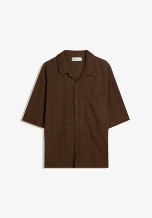 Rjava kratka majica s kratkimi rokavi, izdelana iz teksturirane tkanine z izrezljanimi vzorci, z ovratnikom in enim žepom na prsih. Zapiranje na gumb.