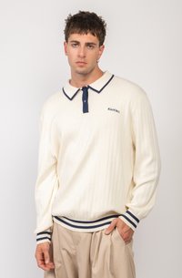 Camisa polo de manga larga de canalé crema con cuello y botón en azul marino; presenta el logo "Kaotiko" en el pecho y puños a rayas.