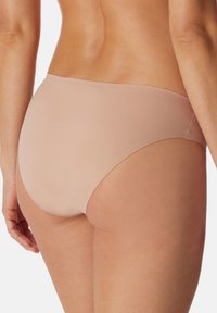 Beige bikini-trusser lavet af glat stof, med en lavtaljet design og sømløse kanter for et strømlinet udseende.