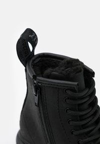 Stivale alla caviglia nero in pelle con una finitura texturizzata. Caratterizzato da una cerniera laterale, lacci rotondi e un colletto imbottito per il comfort.