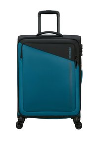 Una valigia rigida di colore teal con superficie testurizzata, dettagli neri, manico telescopico e quattro ruote per la mobilità. Presenta una tasca con zip.