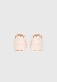 Világos rózsaszín sportcipők hálós felsőrésszel, párnázott szegéllyel, párnázott talppal és texturált díszítésekkel a saroknál és az oldalpanelekben.