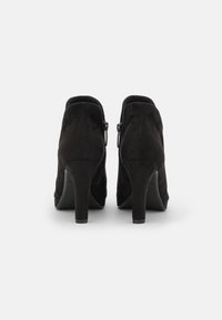 Schwarze Wildleder-Stiefeletten mit glatter Textur, ausgestattet mit einem schmalen Absatz und seitlichen Reißverschlüssen. Einfache, elegante Form ohne Verzierungen.