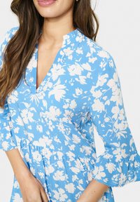 Rochie florală albastră cu accente albe, având decolteu în V, mâneci 3/4 cu volănașe și talie strânsă. Material moale, ușor.