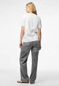 Camiseta de algodón blanca con mangas cortas, combinada con jeans de mezclilla grises de tiro alto y corte holgado. Diseño sencillo, sin patrones visibles.