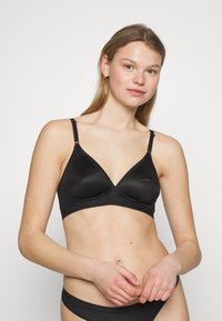 Black triangular bra made of smooth fabric. Features adjustable straps and a wide band with subtle logo detailing at the bottom.