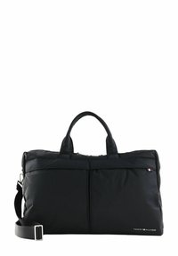 Schwarze Nylon-Reisetasche mit zwei kurzen Griffen und einem abnehmbaren Schultergurt. Verfügt über eine vordere Reißverschlusstasche und ein Logodetail an der Seite.