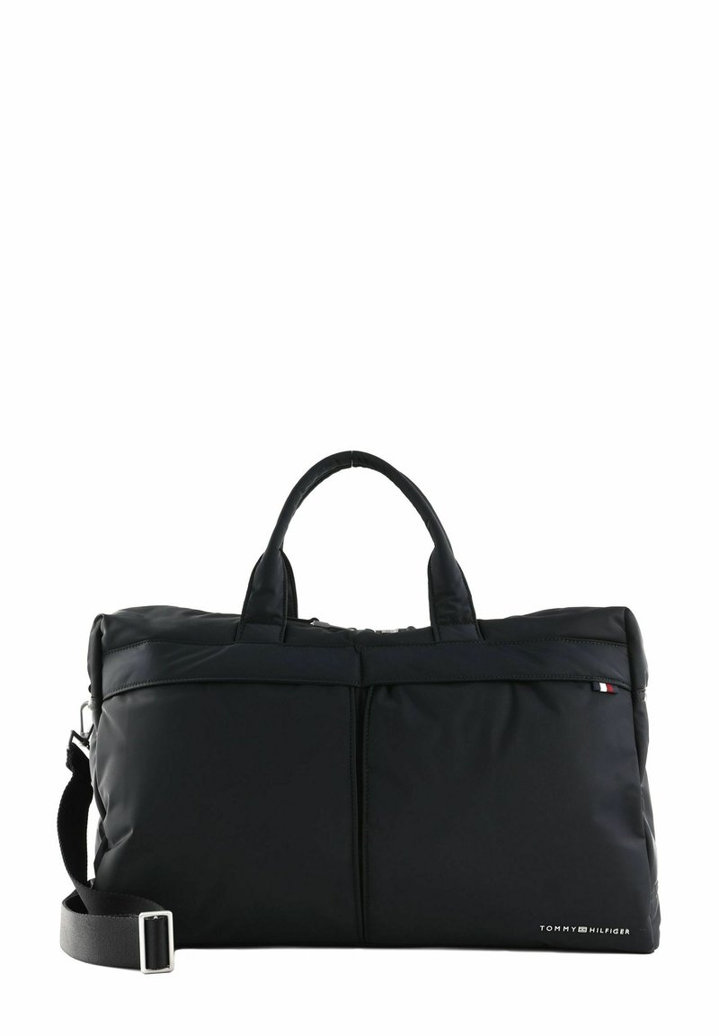 Schwarze Nylon-Reisetasche mit zwei kurzen Griffen und einem abnehmbaren Schultergurt. Verfügt über eine vordere Reißverschlusstasche und ein Logodetail an der Seite.