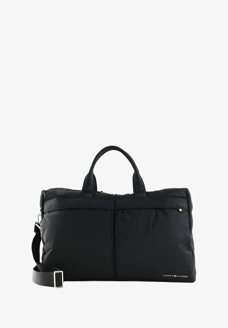 Schwarze Nylon-Reisetasche mit zwei kurzen Griffen und einem abnehmbaren Schultergurt. Verfügt über eine vordere Reißverschlusstasche und ein Logodetail an der Seite.